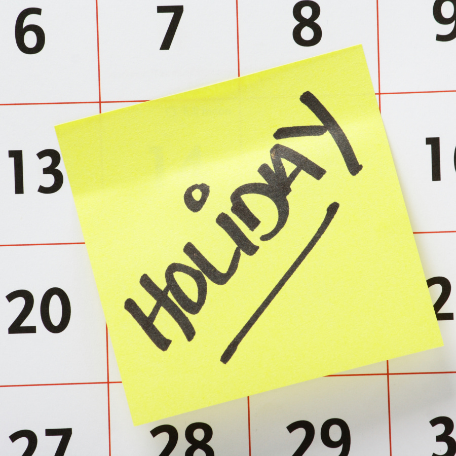 yellow sticky note with the word holiday on a calendar